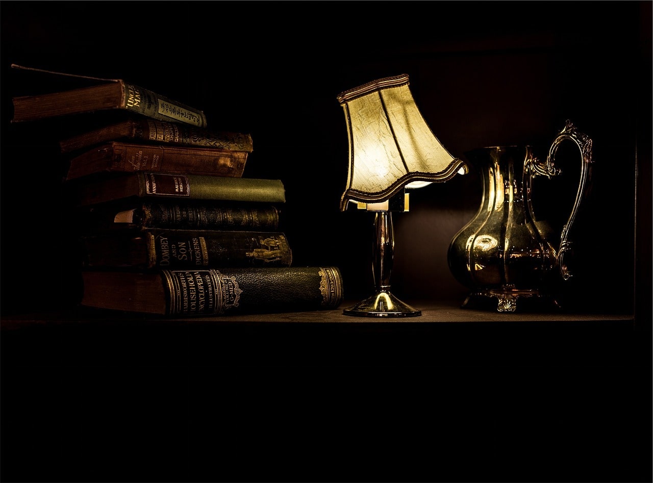 L'illustration montre une lampe de chevet vintage près d'une pile de livres.